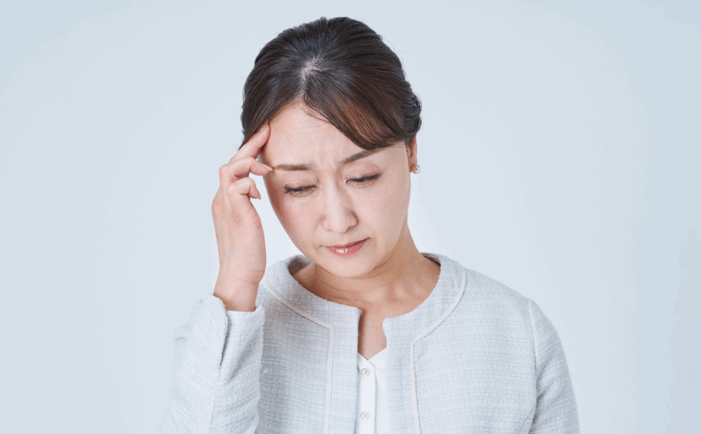 ストレスに頭を抱える女性。痛みとストレスは密接にかかわっていることを示す写真。
