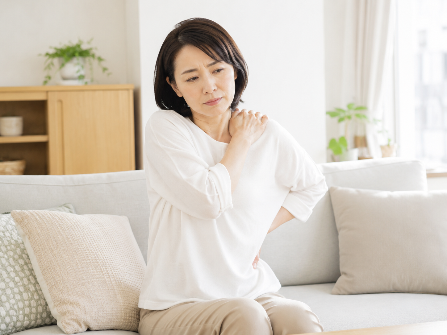 整体後の張り返しや筋肉痛が気になり、肩と腰に手を当てて不安そうにする女性