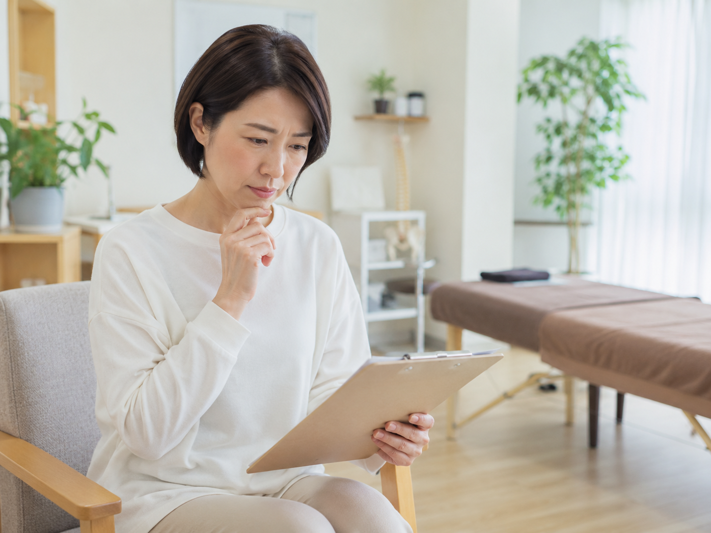 整体院で問診票を見ながら、一回で良くなるのか不安そうに相談する女性